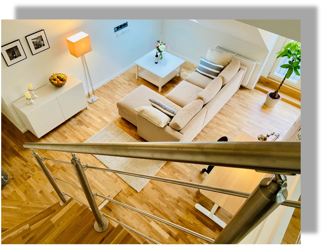 Galerieblick auf den möblierten Wohnbereich eines Maisonette-Apartments